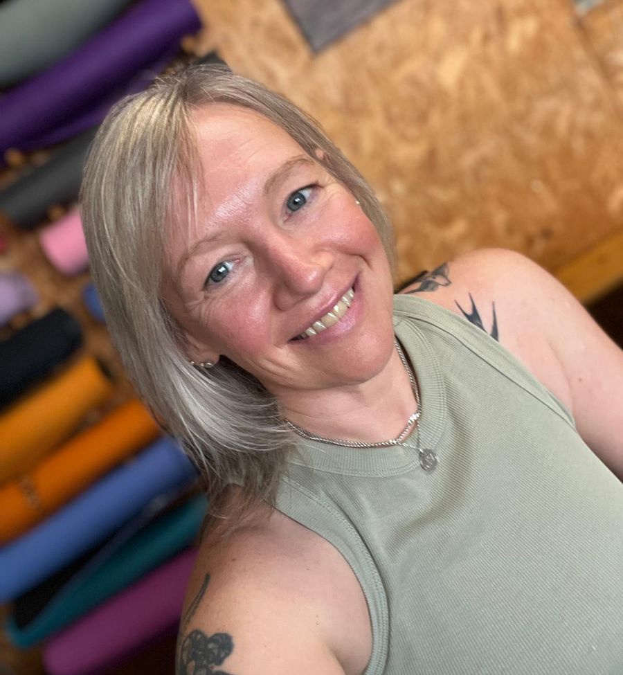 Helen smiling in front of the wall of yoga mats